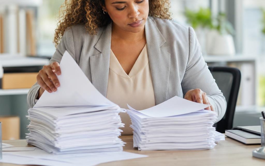 An analyst comparing two separate stacks of loan documents side by side