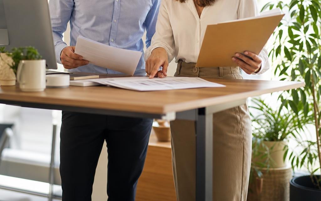 Two colleagues reviewing entity formation paperwork at a standing desk